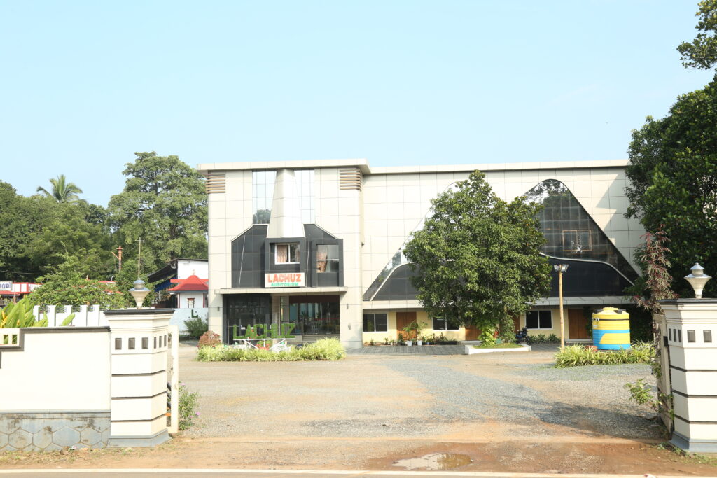 Exterior view of a modern auditorium designed and built by KLBUILD CONTRACTORS, featuring a sleek facade, large glass windows, and a spacious entrance area.